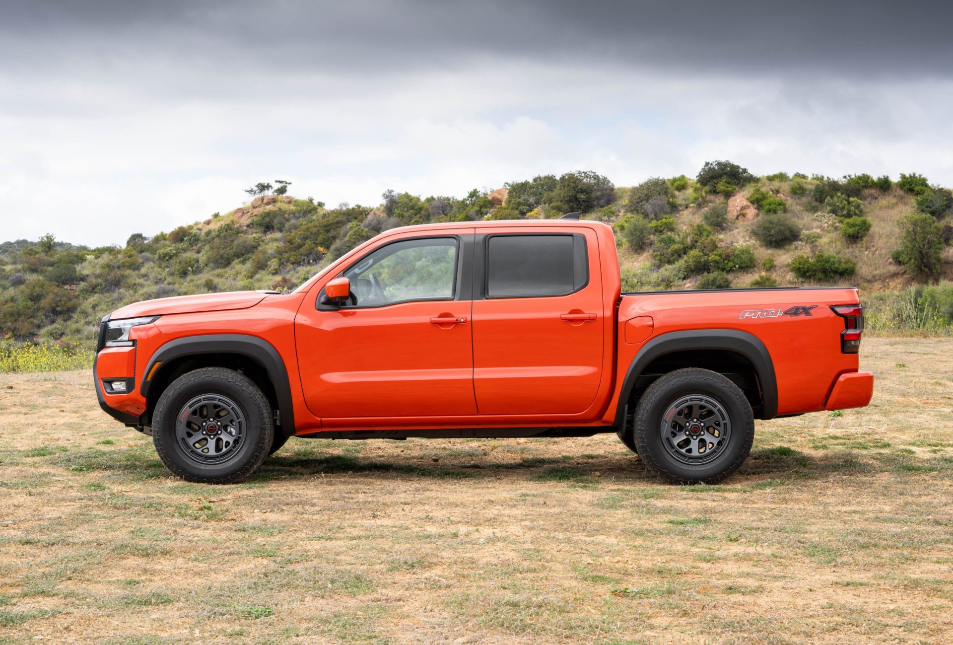 Nissan Frontier 2025 vue de profil et stationné sur l'herbe en pleine campagne